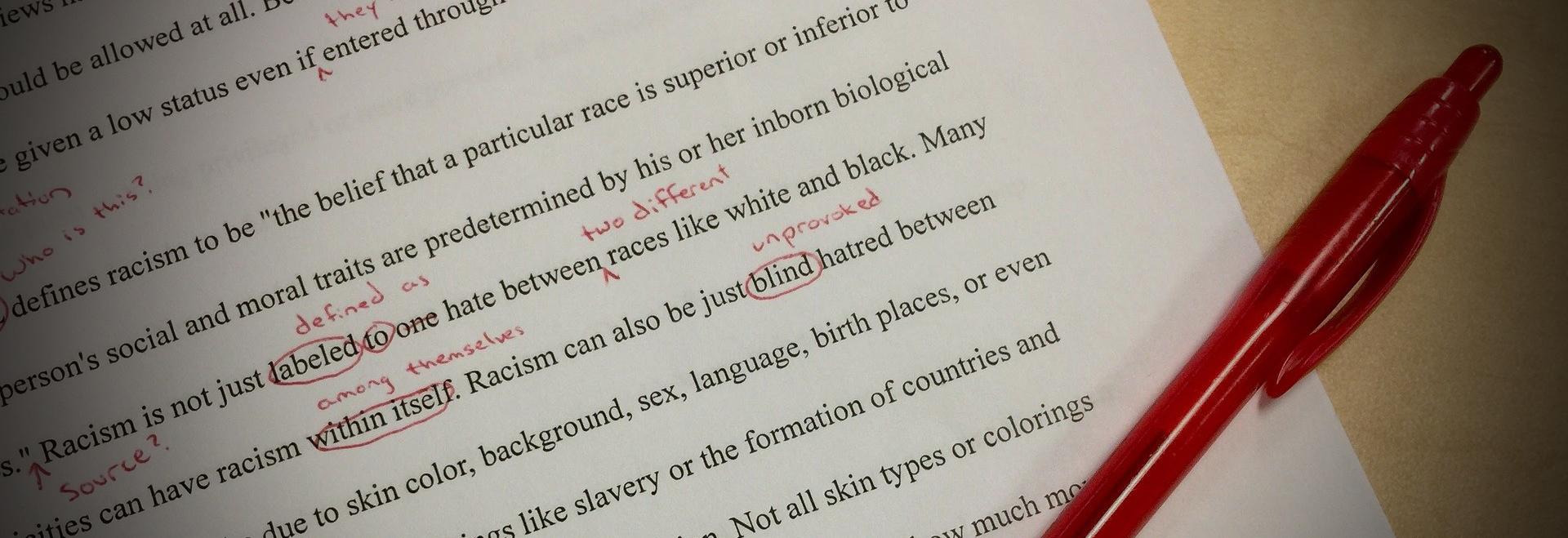 A student paper about race is marked up with red ink corrections.
